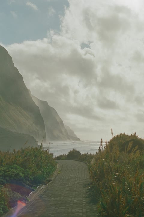 A coastal path running toward sea cliffs under a cloudy sky