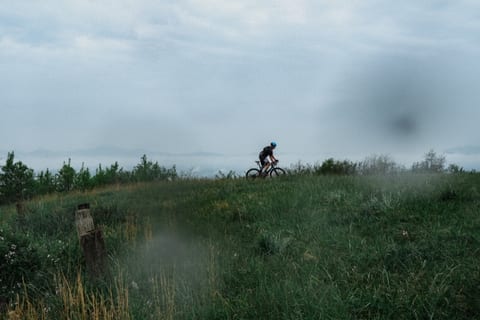 A lone rider along a grassy ridge under low cloud