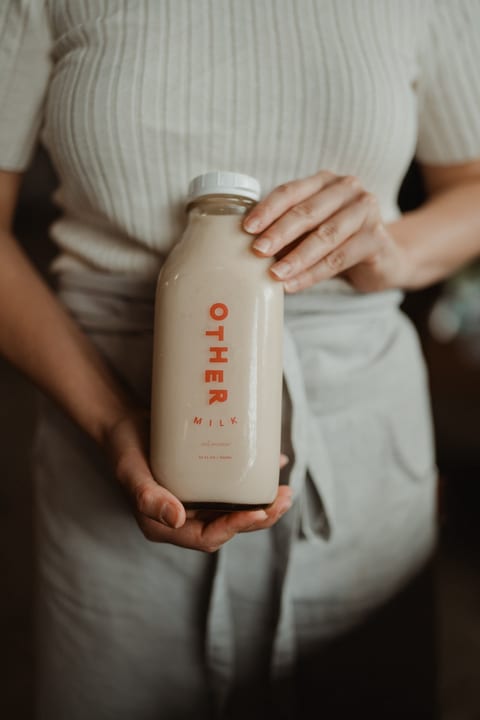 Two hands holding a bottle of Other Milk
